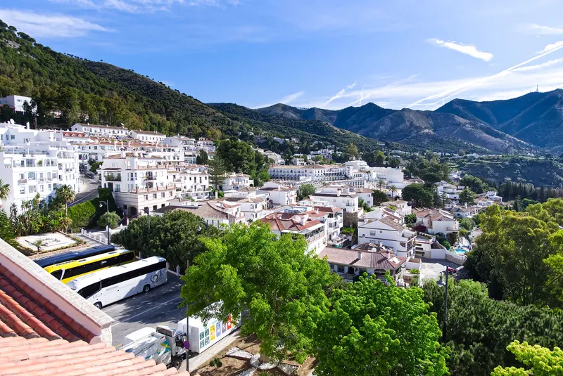 Casas blancas de Mijas Pueblo entre pinos, con la sierra al fondo